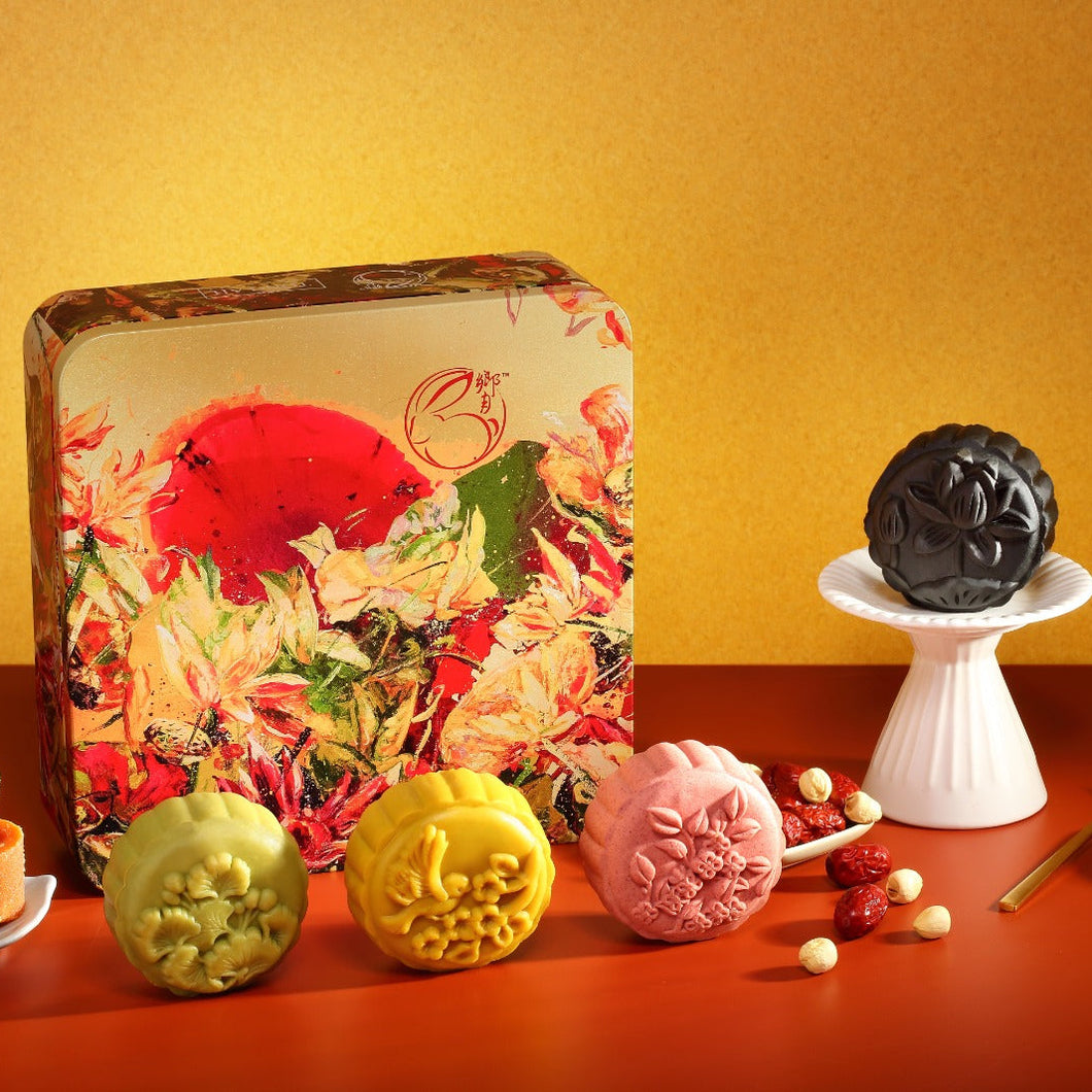 Assorted mooncakes in front of a decorative box on a red surface with a yellow background